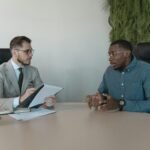 Two businessmen engaged in a discussion during a job interview in a contemporary office environment.